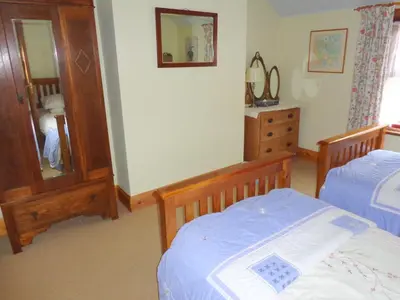 a bedroom with two beds and a mirror and a dresser at Ballacowell Cottage in Sulby