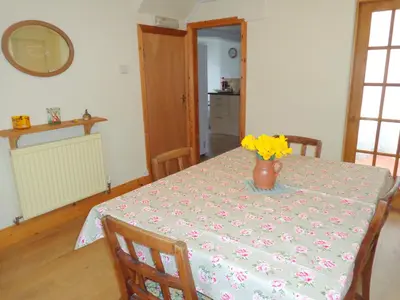 a dining room table with a vase of flowers on it at Ballacowell Cottage in Sulby