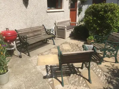two park benches and a table in a patio at Ballacowell Cottage in Sulby