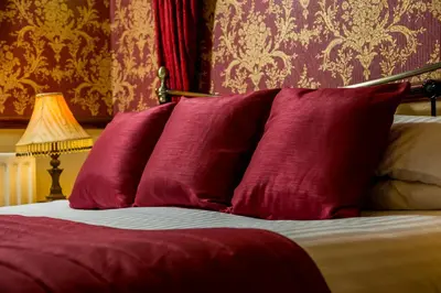 a group of red pillows on a bed with a lamp at Brookfield B&B Guest House in Keswick
