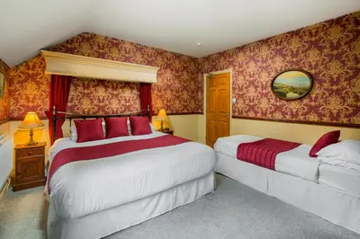 two beds in a room with red wallpaper at Brookfield B&B Guest House in Keswick