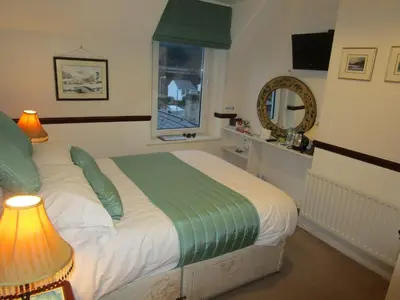 a bedroom with a bed and a window and a mirror at Brookfield B&B Guest House in Keswick