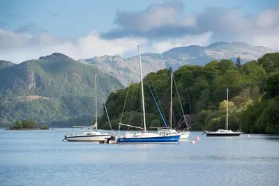three boats in the water with mountains in the background at The Mount self-catering in Portinscale