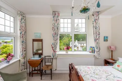 a bedroom with a bed and two windows at The Mount self-catering in Portinscale