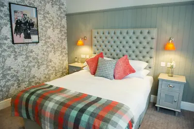 a bedroom with a large bed with red pillows at Crown Hotel Wetheral in Carlisle
