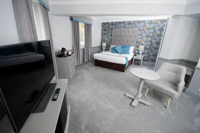 a bedroom with a bed and a table and a chair at Crown Hotel Wetheral in Carlisle