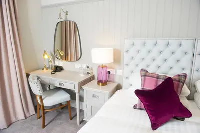 a bedroom with a desk and a bed with a white bedspread at Crown Hotel Wetheral in Carlisle