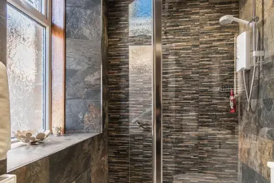 a glass shower in a bathroom with a brick wall at Inverlea Guest House in Ayr