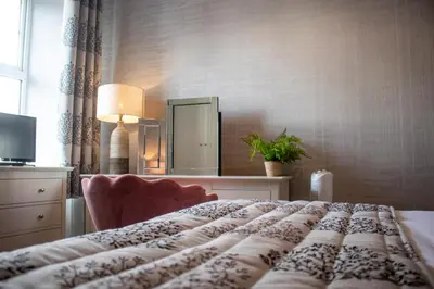 a bedroom with a bed with a dresser and a mirror at The Loans Inn in Troon