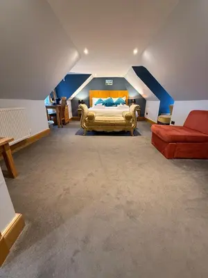 a bedroom with a bed and a red couch at The Ship Inn - Winner Best Hotel Experience 2024 Visit Scotland in Gatehouse of Fleet