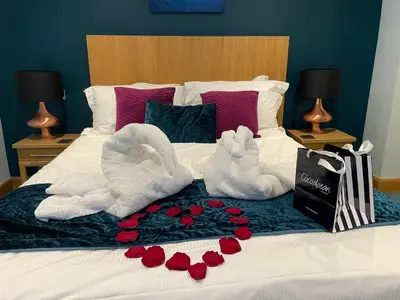 two swans are sitting on a bed with roses at The Ship Inn - Winner Best Hotel Experience 2024 Visit Scotland in Gatehouse of Fleet