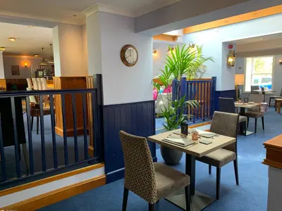 a restaurant with a table and chairs and a clock at The Ship Inn - Winner Best Hotel Experience 2024 Visit Scotland in Gatehouse of Fleet