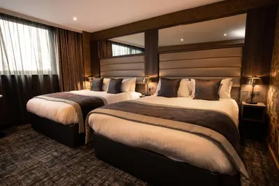 a hotel room with two beds and a mirror at Carlton Hotel in Prestwick