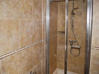 a shower stall in a bathroom with brown tiles at Chaucers Nook in Keswick