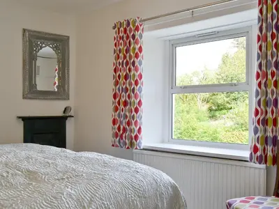 a bedroom with a bed and a window with curtains at 3 Barf Cottages in Portinscale