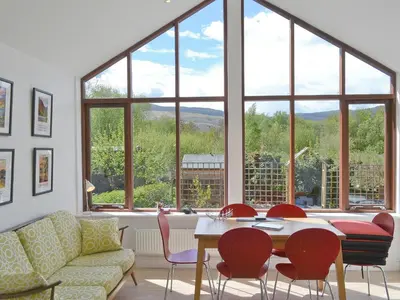 a living room with a table and chairs and a large window at 3 Barf Cottages in Portinscale