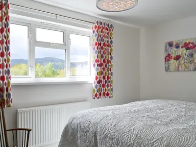 a bedroom with a bed and two windows at 3 Barf Cottages in Portinscale