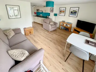 a living room with a couch and a table and a tv at 5 Balmoral House in Keswick