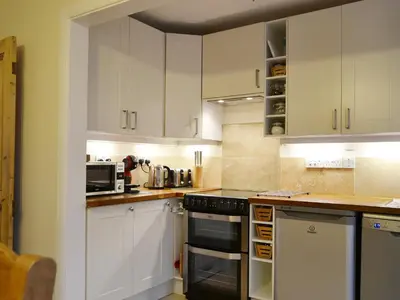 a kitchen with white cabinets and a stove top oven at Beny Cot in Keswick