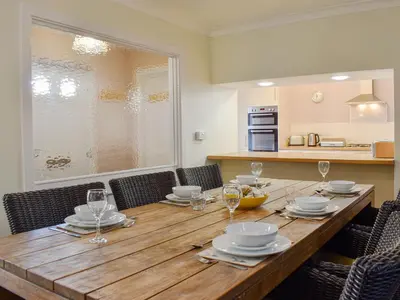 a wooden table with plates and wine glasses on it at Oak Apple House in Keswick