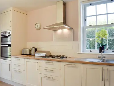 a kitchen with white cabinets and a sink and a window at Oak Apple House in Keswick