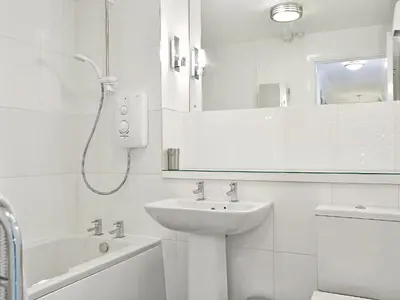 a white bathroom with a sink and a mirror at Herdwick Heights in Keswick