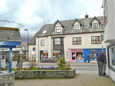 a man standing on a sidewalk in front of a building at Herdwick Heights in Keswick