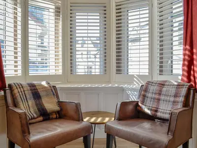 two chairs and a table in a room with windows at Bag End in Keswick