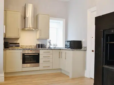 a kitchen with white cabinets and a window at Bag End in Keswick