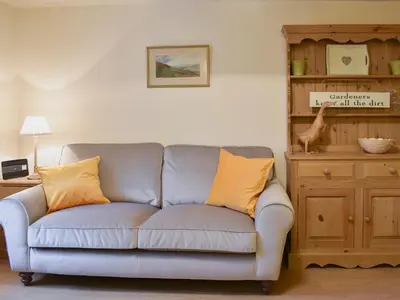 a living room with a gray couch with yellow pillows at Harriet's Hideaway in Braithwaite