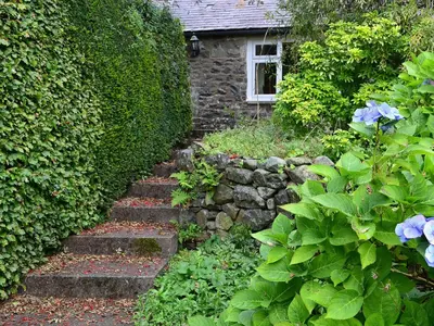 a garden with a stone path leading to a house at Dye Mill Cottage in Moffat