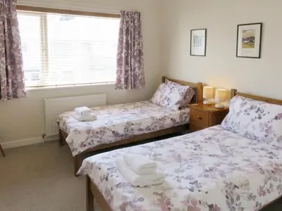 a bedroom with two beds and a window at Heatherside in Portinscale