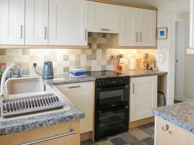 a kitchen with white cabinets and a black dishwasher at Heatherside in Portinscale