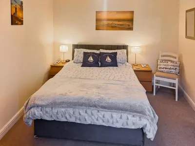a bedroom with a large bed with two tables and a chair at Harbour Retreat in Garlieston