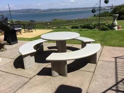 a picnic table and two benches with a view of the water at Thornbank House in Stranraer