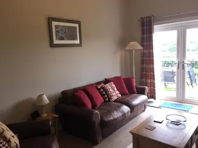 a living room with a brown couch with pink pillows at Old Station House - Kilfillan Cottage in Garlieston