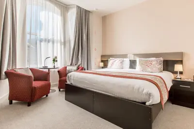 a bedroom with a large bed and two chairs at Mannin Hotel in Douglas