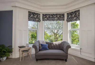 a living room with a couch and two windows at Baie Mooar House, Boutique B&B in Ramsey