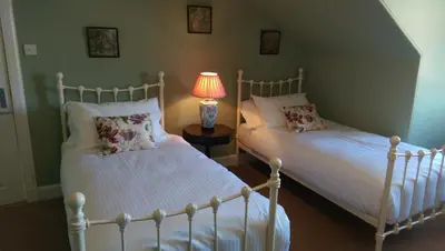 two beds in a room with a lamp on a table at Lochinver Guesthouse in Ayr