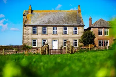 an old stone house with a gate in front of it at Ann's Hill in Cockermouth