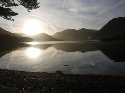 a lake with the sun reflecting on the water at Ann's Hill in Cockermouth