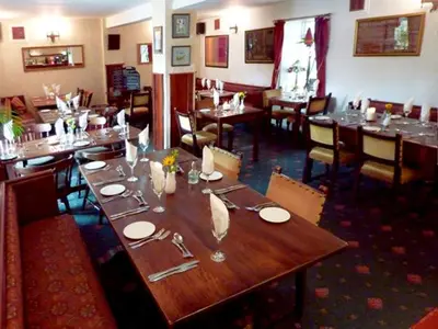 a dining room with a large wooden table in a restaurant at The Douglas Hotel in Langholm