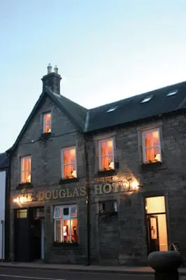 a large brick building with lights in the windows at The Douglas Hotel in Langholm