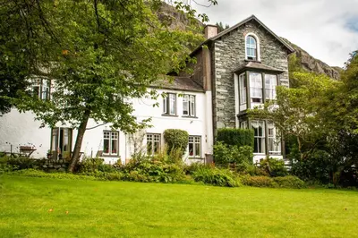 a house with a green lawn in front of it at The Old Dungeon Ghyll Hotel in Great Langdale