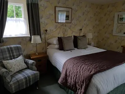 a hotel room with a bed and a chair at The Old Dungeon Ghyll Hotel in Great Langdale