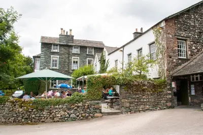 a group of people sitting at a table in front of a building at The Old Dungeon Ghyll Hotel in Great Langdale
