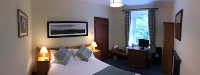 a bedroom with a bed and a desk and a window at Old Water View in Patterdale