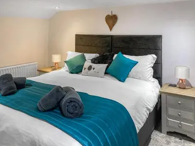 a bedroom with a large bed with blue sheets and pillows at Cosy Cottage in Portinscale