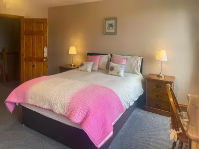 a bedroom with a large bed with a pink blanket at Bay Cottage in Keswick