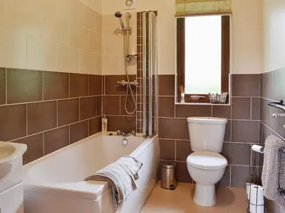 a bathroom with a tub and a toilet and a sink at Rowanburn Lodge in Ellonby